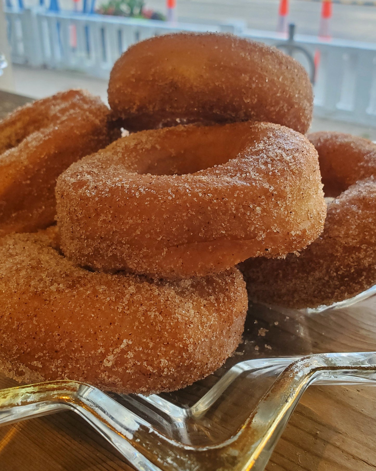 Round classic style cinnamon sugar donuts displayed on a glass stand in a window