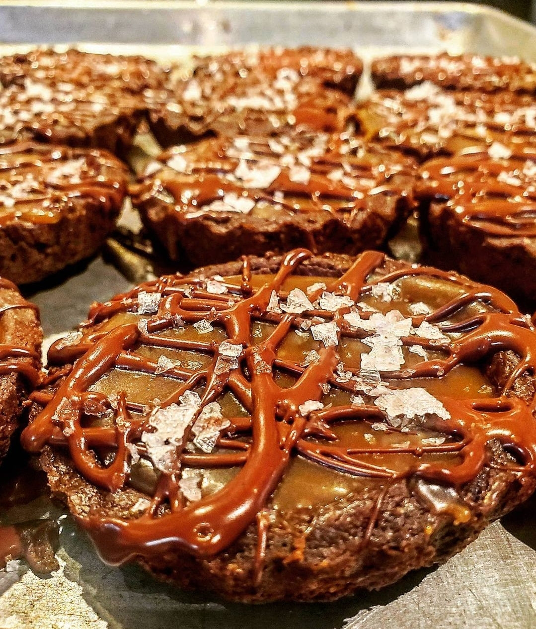 Chocolate tarts with caramel filling topped with chocolate drizzle and sea salt